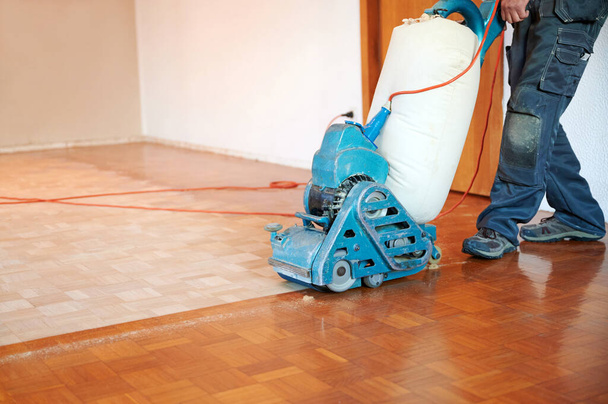 Worker polishing parquet floor with grinding machine - Foto, imagen
