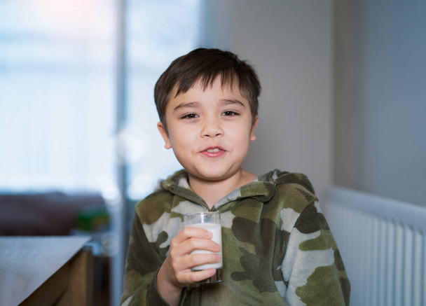 Ritratto ragazzo della scuola sano bere un bicchiere di latte per la prima colazione, Bambino felice seduto in sala da pranzo bere latte caldo prima di andare a scuola. Concetto di Healhty food liftstyle - Foto, immagini
