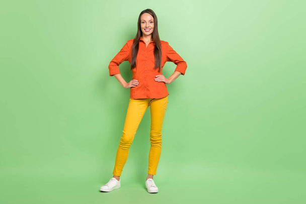 Full size photo of young pretty woman arms on waist agent representative isolated over green color background - Foto, afbeelding