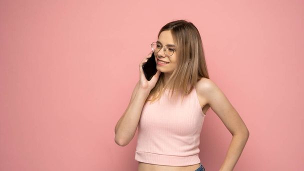 Young blonde woman over isolated pink background sending a message with the mobile. - Foto, afbeelding