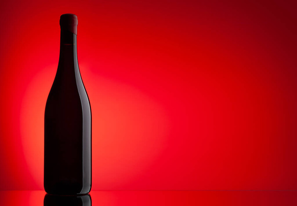 Botella de vino tinto sobre fondo rojo con espacio de copia - Foto, imagen