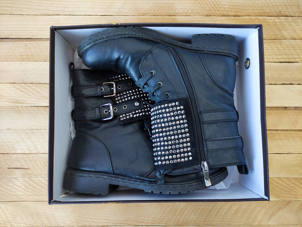 Black women's leather boots with rhinestonesin in the box on a wooden background - Photo, Image