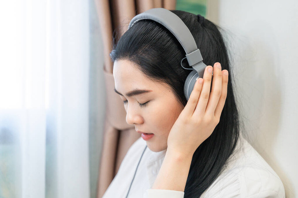 Eine junge Studentin entspannt sich, hört Musik, während sie am Wochenende zu Hause studiert - Foto, Bild