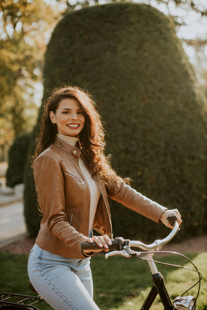 Досить молода жінка їде на велосипеді в осінній день
 - Фото, зображення