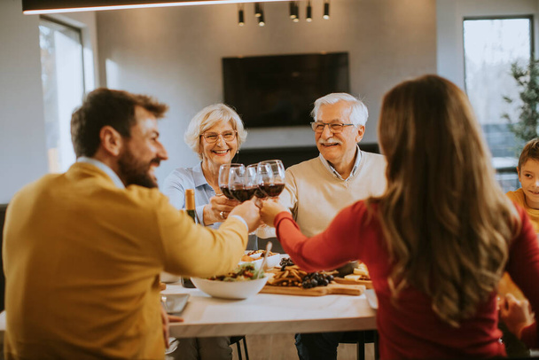 幸せな家族は家で赤ワインと夕食を持っています - 写真・画像
