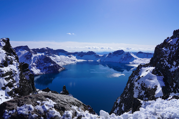 冬の雪の後ろの青い火山湖、中国と北朝鮮の国境にある長白山の天池の北斜面 - 写真・画像