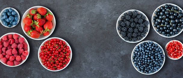 Berries in plates on a black concrete background. Copy space. Flat top view. - Fotografie, Obrázek