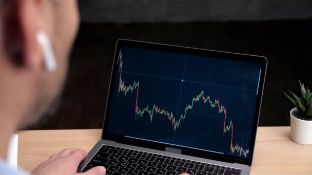 Uomo testa stock trader broker utilizza laptop con schermo grafico borsa - Filmati, video