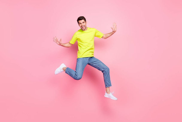 Full body photo of funny brunet hairdo millennial guy jump wear green t-shirt jeans isolated on pink color background - Fotografie, Obrázek