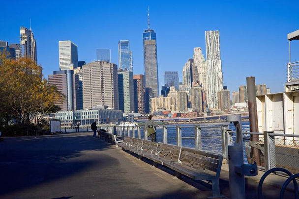 Brooklyn, NY, Estados Unidos - 15 de diciembre de 2021: El horizonte del Bajo Manhattan se ve desde el paseo marítimo de Brooklyn mirando al otro lado del East River - Foto, Imagen