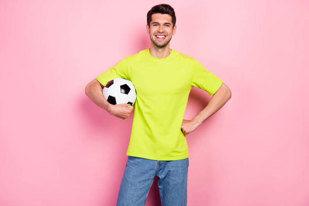 Photo portrait smiling man wearing bright t-shirt keeping soccer ball isolated pastel pink color background - Фото, изображение