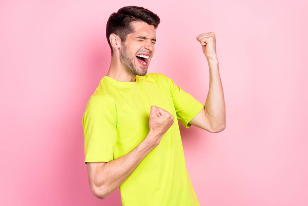 Photo portrait cheerful brunet man wearing bright t-shirt overjoyed gesturing like winner isolated pastel pink color background - Photo, image