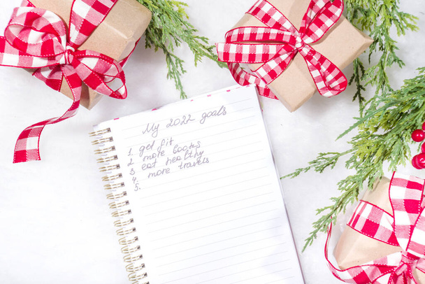 Psaní plánu na rok, novoroční řešení. Zápisník s nápisem Moje cíle 2022, na sněhobílém kožešinově načechraném pozadí, s novoročními dárky a větvemi vánočních stromků - Fotografie, Obrázek
