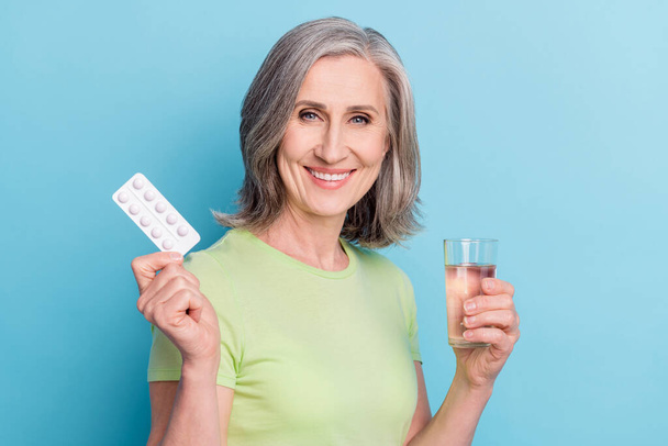 Photo of pretty nice charming old woman hold hand glass of water pills isolated on pastel blue color background - Photo, Image