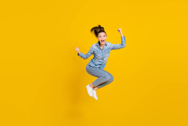 Full length body size photo young pretty girl jumping up gesturing like winner isolated bright yellow color background - Foto, Imagen