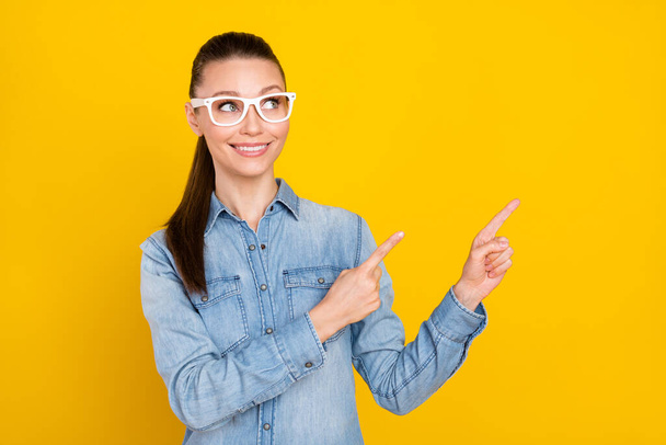 Portrait of attractive cheerful girl demonstrating copy space ad look idea new novelty isolated over bright yellow color background - Φωτογραφία, εικόνα