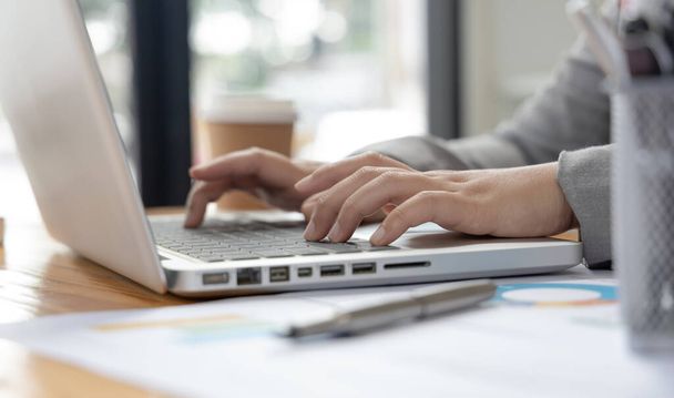 Рука предпринимательницы нажимает на клавиатуру ноутбука, используя компьютеры для проведения финансовых операций, потому что удобство и скорость, Мир технологий и интернет-коммуникаций. - Фото, изображение