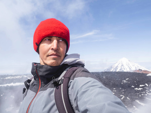Tourist makes selfie on Avachinsky volcano. Koryaksky or Koryakskaya Sopka on background. Natural landmarks of Kamchatka Peninsula. Russia. - Foto, Imagem