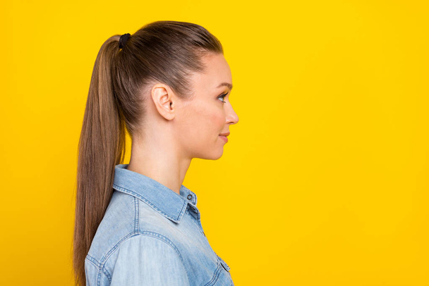 Photo of sweet charming young woman wear denim shirt smiling looking empty space isolated yellow color background - Φωτογραφία, εικόνα
