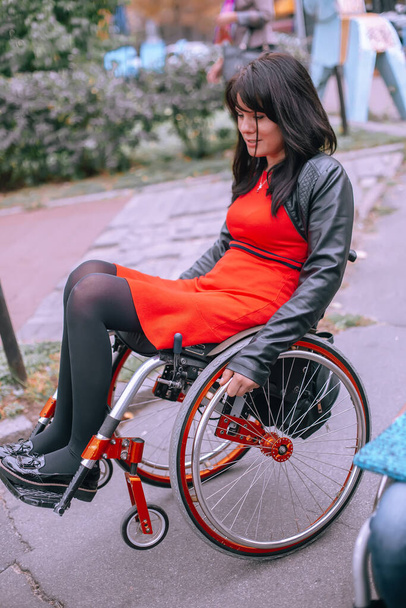 Дівчина в інвалідному візку їде по слайду з піднятими передніми колесами. Труднощі пересування для людей з особливими потребами. Доступне місто
 - Фото, зображення