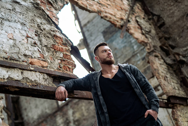 Brutal man posing with mindful expression. Sexy male on abandoned building background. Stock photo - Foto, immagini