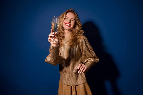 Laughing girl holding out glass of champagne to camera - Foto, Imagem