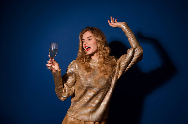 Веселая девушка смотрит на бокал шампанского в руке - Фото, изображение