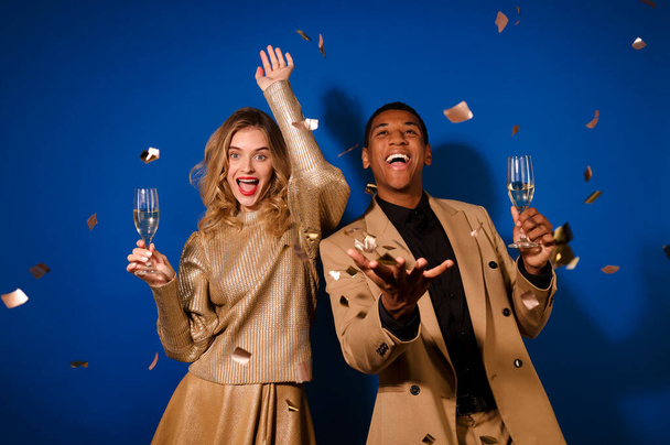 Парень и девушка с шампанским радуются летающим конфетти - Фото, изображение