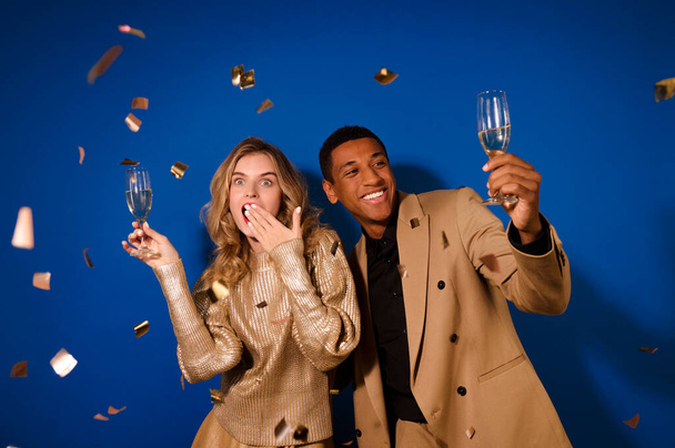 Zaskoczona dziewczyna i uśmiechnięty facet z szampanem i latającym konfetti - Zdjęcie, obraz