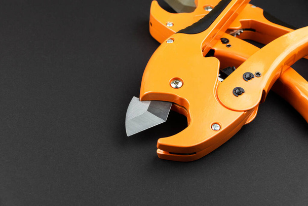 orange scissors for cutting propylene pipes on a black background - Photo, image