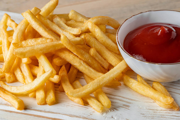 Hot golden french fries with sauce on a wooden background. Homemade rustic food. - Photo, Image