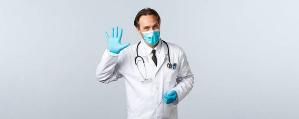 Covid-19, preventing virus, healthcare workers and vaccination concept. Professional doctor at clinic explain five steps to protect health from infection, wearing medical mask and gloves - Photo, image