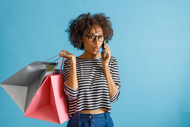 Hämmästynyt nainen ostoskassit puhuu matkapuhelimella - Valokuva, kuva