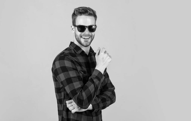 well groomed hairstyle. male beauty and fashion look. checkered shirt for bearded guy. unshaven handsome man with bristle in sunglasses. hairdresser concept. young and confident - Фото, изображение