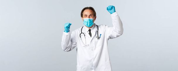 Covid-19 、ウイルス、医療従事者および予防接種の概念を防止する。医療用マスクと手袋の支援医師を軽減、叫びとして手を上げ、目標の達成を祝う - 写真・画像