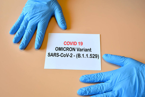 Covid-19 nieuwe Omicron variant. Doctor handen met blauwe handschoenen en wit papier met tekst "Covid-19 variant Omicron". - Foto, afbeelding
