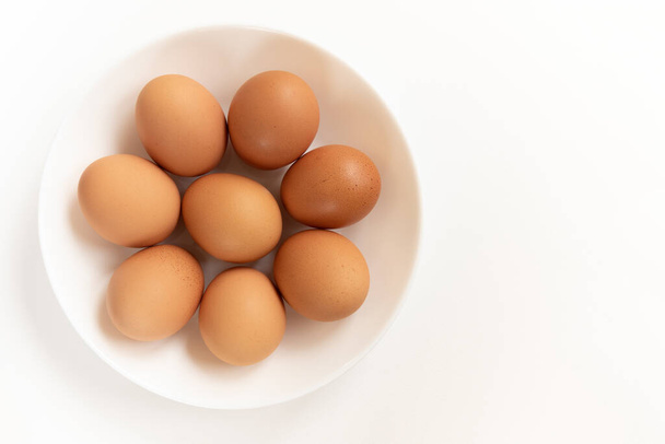 Group of fresh eggs. Brown chicken eggs, isolated on white background. Preparation for painting Easter eggs. Top view - 写真・画像