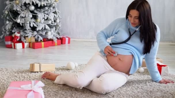 bella donna incinta aspetta il parto all'albero di Natale nuovo anno - Filmati, video