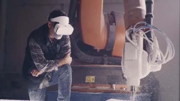 Ремесленник в наушниках VR рядом с роботизированной рукой - Кадры, видео