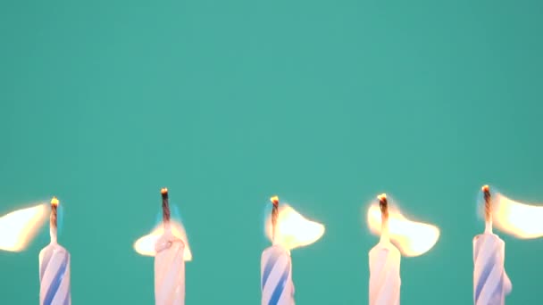 Happy Birthday concept Gemaakt van Brandende Kleurrijke Kaarsen op blauwe of turquoise achtergrond. Vijf jaar verjaardagskaarsen branden. Full HD-video in slow motion. - Video