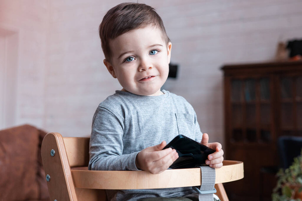 Cute little toddler boy playing with smartphone Healthy baby touching mobile phone with fingers, looking cartoons and having fun with educational apps. Child at home - Photo, image