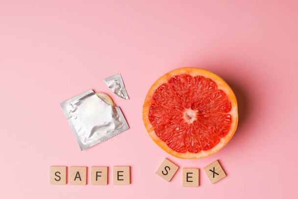 Turvallista seksiä ja naisen terveyttä. Studio laukaus avoin kondomi vieressä greippi  - Valokuva, kuva