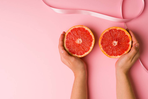 Junge Frau berührt Grapefruits und zeigt, wie man eine Selbstuntersuchung an den Brüsten durchführt, um Krebs zu verhindern - Foto, Bild