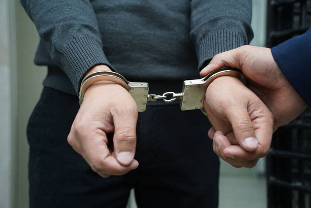 Офицер полиции надел наручники на подозреваемого - Фото, изображение