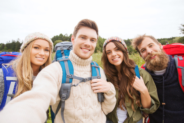 group of smiling friends with backpacks hiking - Fotó, kép