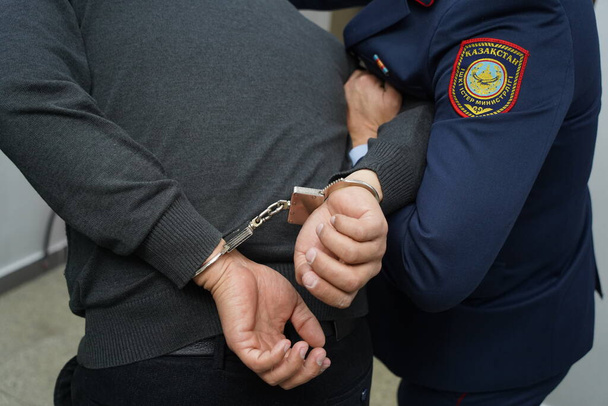 Ein Polizist legt einem Verdächtigen Handschellen an - Foto, Bild