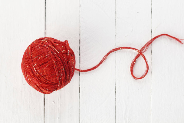 a ball of red yarn on a white background of painted boards. - Photo, Image