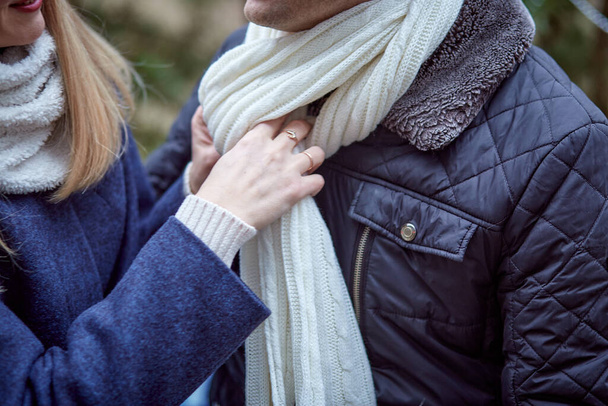  Vrouw recht sjaal van haar man close-up. Romantiek, zorgzaamheid en liefde concept. Verliefd buiten. Winter  - Foto, afbeelding