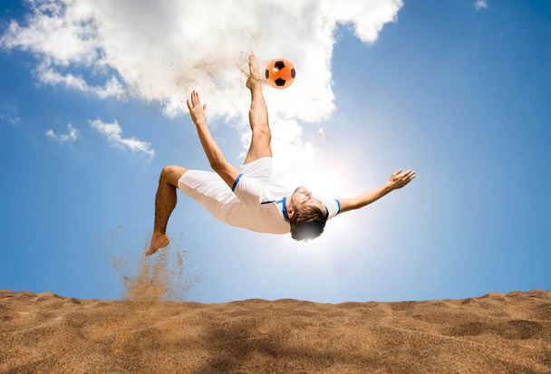 The man footballers are desperately playing beach soccer on sand on a sunny day. Man doing kick on beach with soccer ball - Fotoğraf, Görsel