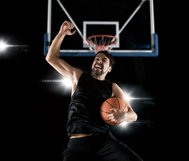 Basketball player celebrating win on dark background - Valokuva, kuva